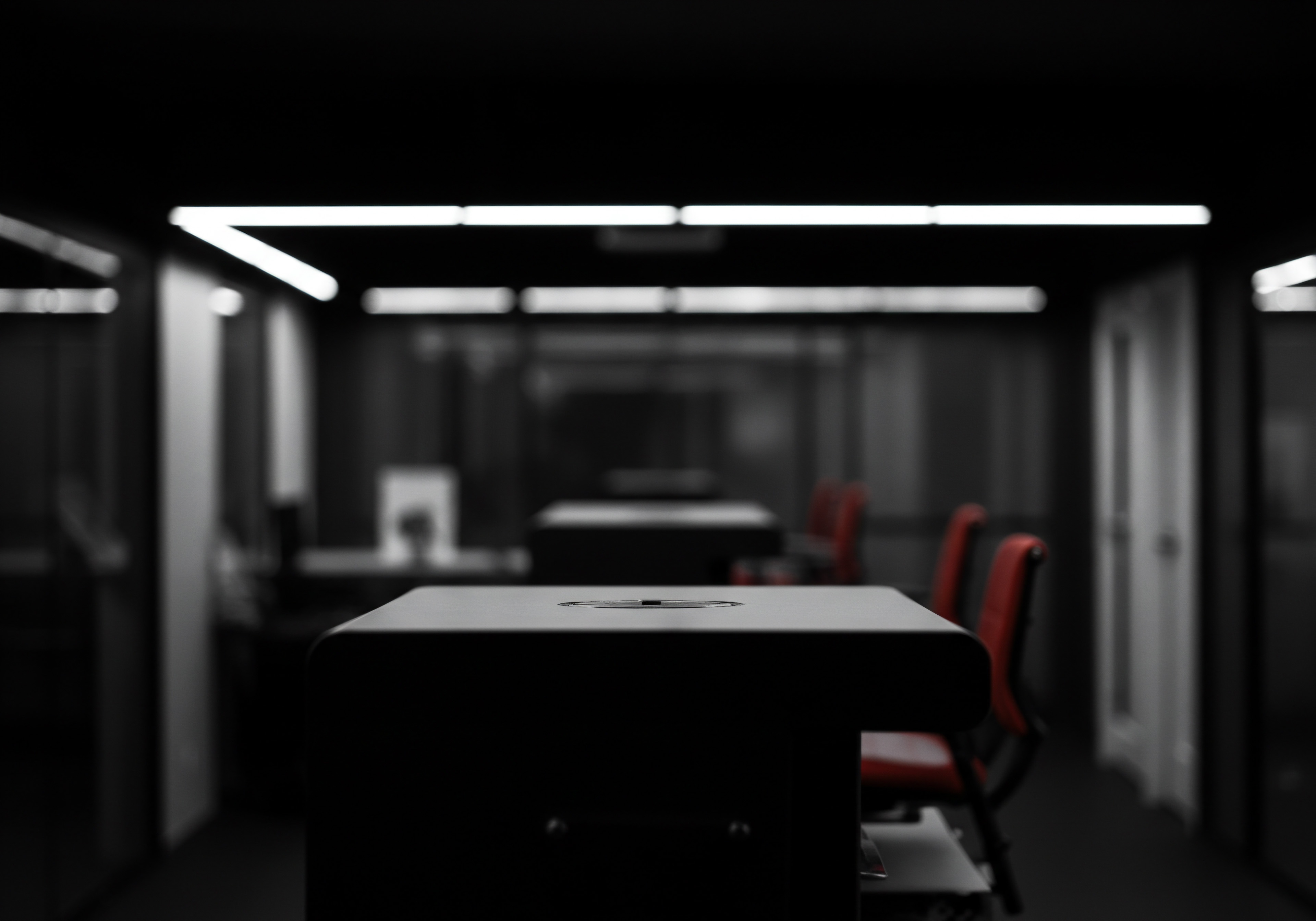 The stark interior presents an evocative scene relevant to SMB business strategy featuring a modern workplace, likely intended for coworking or a collaborative team. Desks equipped with technology dot the space, underlighting from ceiling fixtures to represent illumination and insight in industry. This environment is conducive to professional services, potentially housing consulting firms or marketing agencies serving clients. The dark hues contrasted with stark lines invoke ideas of innovation, while the orderly arrangement represents process, workflow, and the digital transformation strategies critical for success. Scaling a SMB needs strategic planning for optimization and operational efficiency, essential elements for a local business’s success in a competitive market. Business automation and data analytics would enable performance improvements as SMB’s seek growth.