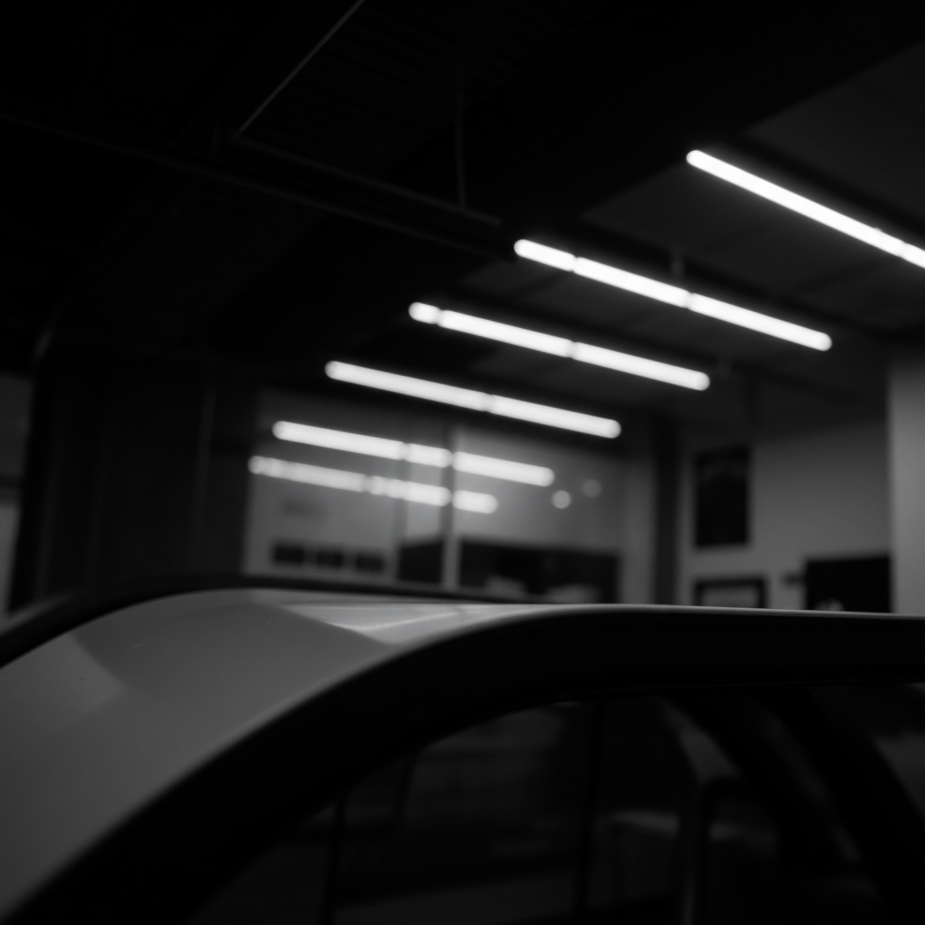 Small Business Strategy Automating Workplace for Operational Efficiency and Business Technology Monochrome shows a focus on streamlined processes within an SMB highlighting the promise of workplace technology to enhance automation. The workshop scene features the top of a vehicle against ceiling lights. It hints at opportunities for operational efficiency within an enterprise as the goal is to achieve substantial sales growth.