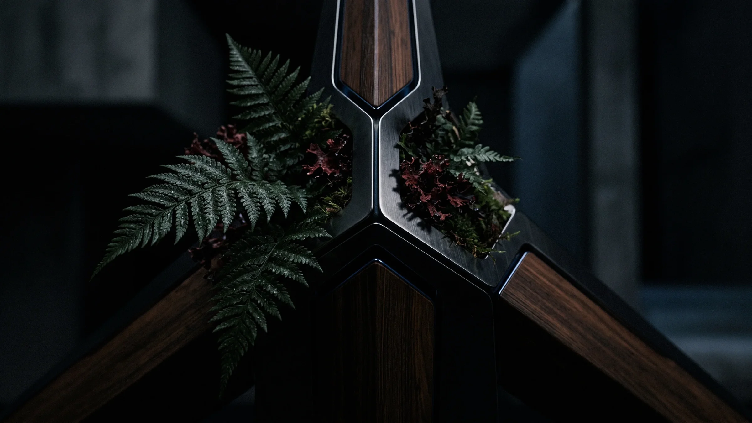 Fern fronds and a tuft of moss tucked into a three-way joint of metal and wood.
